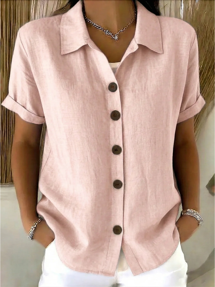 Camicia classica a bottoni rosa drappeggiata su sfondo neutro